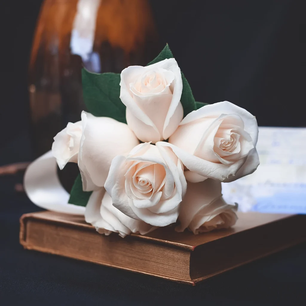 Valkoisia ruusuja kirjan päällä