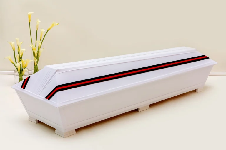 Valkoinen kangaspintainen hauta-arkku jonka kannessa kulkee punamusta raita kuvaamassa Karjalan värejä