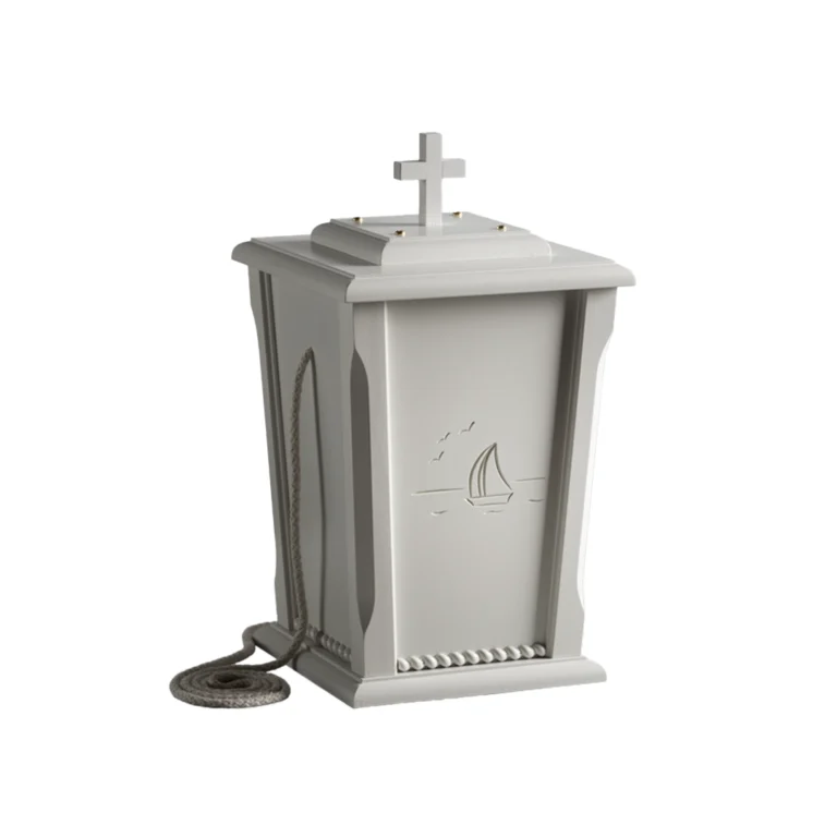 Valkoinen uurna jonka päällä on risti ja kyljessä on kaiverrettuna purjevene